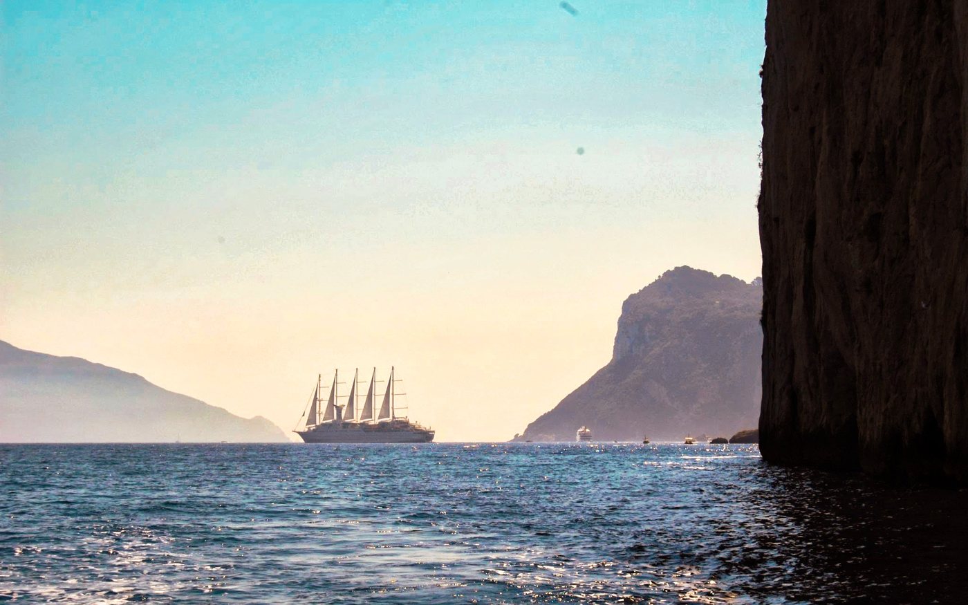 A sailing ship off the Italian coast at dusk